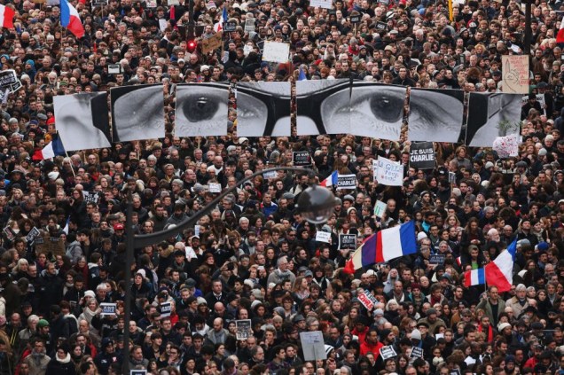 No dia 7 de janeiro, 12 pessoas morreram e 11 ficaram feridas em um tiroteio em Paris. O grupo extremista Al Qaeda na Península Arábica (AQPA), com base no Iêmen, assumiu a responsabilidade pelo ataque terrorista ao semanário satírico francês <em>Charlie Hebdo</em>. O ataque ao <em>Charlie</em> foi o início de três dias de terror na França, que ainda presenciou o assassinato de uma policial e um sequestro com vítimas fatais em um supermercado em Paris. Ao todo, dezessete pessoas foram assassinadas pelos terroristas. Dias depois, pessoas de toda a França se reuniram para protestar. Na foto, os cartazes que montam a imagem de um rosto é uma homenagem ao cartunista Georges Wolinski, que foi morto.