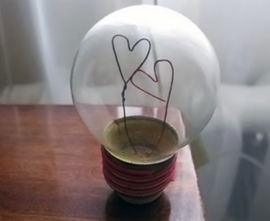 A estrutura desta lâmpada queimada foi usada para fazer um enfeite com formato de coração.