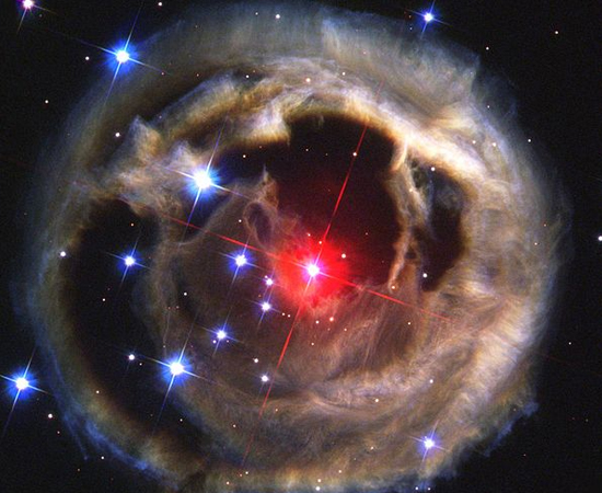 A ESTRANHA - ‘V838 Monocerotis’ é uma hipergigante vermelha, localizada na constelação de Monoceros, é uma das mais brilhantes da Via Láctea. No entanto, em 2002, o brilho da estrela desapareceu repentinamente. Os cientistas então a classificaram como uma simples ‘nova’ - uma designação par o núcleo restante de uma estrela morta, chamada de anã branca. Mas, um mês depois, a estrela voltou a brilhar! Na verdade, V838 não era uma anã branca. Ela só havia entrado em erupção por si mesma. Inclusive, outras erupções ocorreram nos próximos meses. Após este processo, o telescópio Hubble capturou esta imagem que mostra uma nuvem de gás e detritos em volta da estrela.