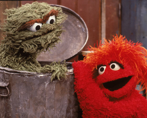 O personagem ´Oscar, o Resmungão´ (Oscar the Grouch) recebe uma visita de outro muppet em sua lata de lixo. A cena é de um episódio de Vila Sésamo, na década de 80.