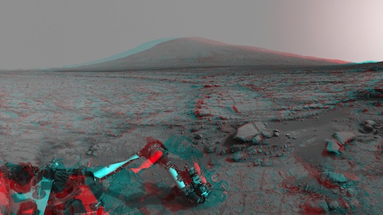 A imagem dessa cratera em Marte foi tirada do Curiosity Rover Mount Sharp. Dentro da cratera, uma montanha de 5km domina o horizonte. Em primeiro plano, o braço robótico da sonda utiliza uma ferramenta para explorar o solo do planeta vermelho.