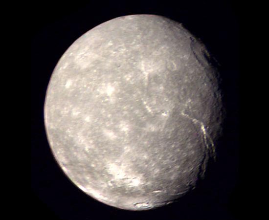 Esta é Titânia, a maior lua de Urano. Sua superfície é cheia de cânions e escarpas. As únicas imagens disponíveis foram tiradas em 1986, durante a missão da sonda espacial Voyager 2. Por isso, apenas 40% do satélite foi mapeado.