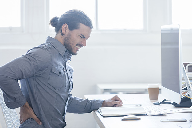 Young business man with holding his back in pain.