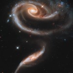 O par de galáxias Arp 23, mostrando a maior (acima) com sua forma distorcida pela menor, que passou por dentro dela.