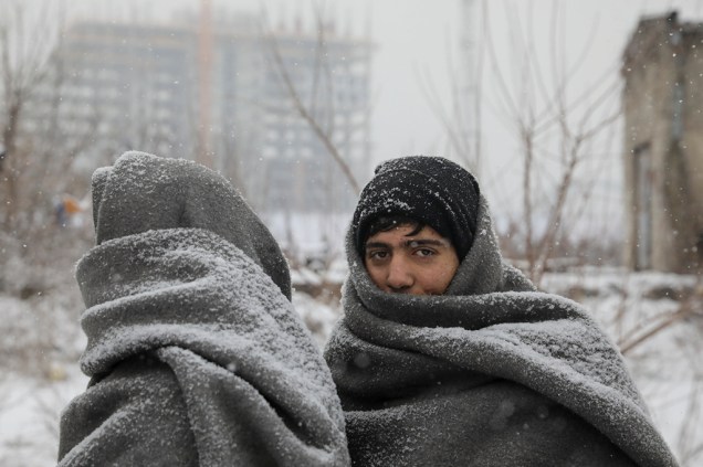 Refugiados tentam se proteger do frio em Belgrado.
