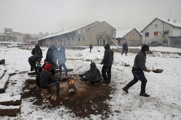 Enquanto a neve cai, refugiados tentam se esquentar em Belgrado.