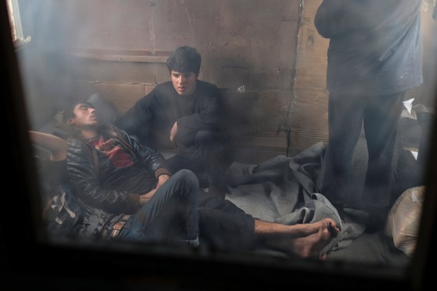 Imigrantes descansam dentro de um vagão abandonado.