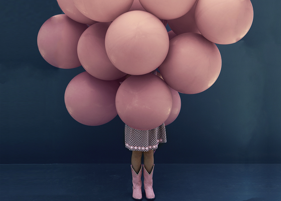 Menina segurando balões rosa.
