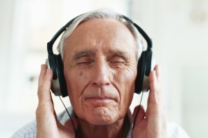 Senior man wearing headphones, eyes closed, close-up