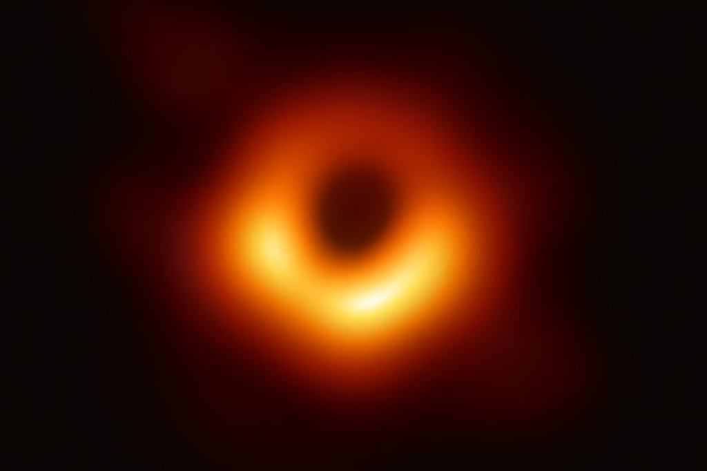 Imagem do buraco negro M87*: uma nuvem laranja em forma de rosquinha, com o buraco negro no centro.