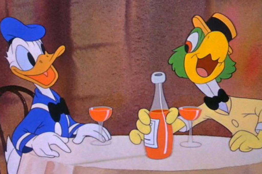 A ilustração mostra o personagem Pato Donald, um pato branco, com o bico laranja, usando uma boina azul e uma camiseta azul com detalhes em branco e uma gravata borboleta preta, sentado em uma mesa, de frente para o personagem Zé Carioca, um papagaio verde, com o bico laranja, que usa um chapéu laranja com uma faixa preta, uma camisa branca com uma gravata borboleta preta e um paletó amarelo. Eles estão sentados numa mesa onde há duas taças e uma garrafa contendo um líquido laranja,