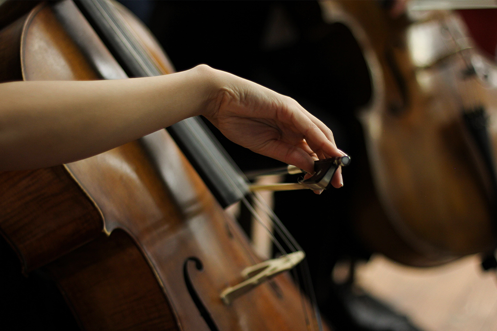 Mão feminina tocando um violoncelo.