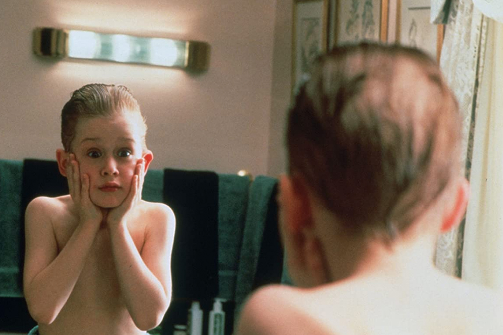 Cena do filme "esqueceram de mim", com o personagem interpretado pelo ator Macaulay Culkin se olhando no espelho e com as mãos no rosto.