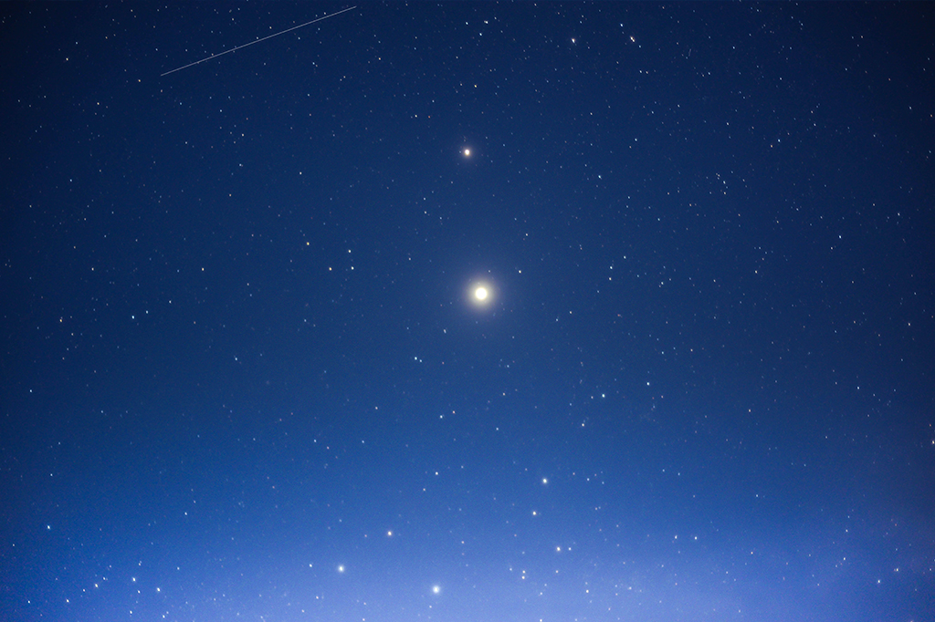Céu azul estrelado, com dois pontos brilhantes no centro: Júpiter e Saturno.