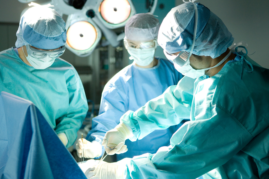 Cirurgiões operando com equipamento cirúrgico.