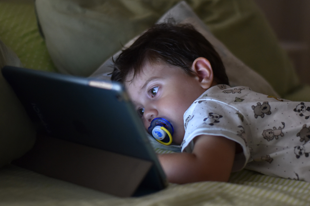 Bebê usando tablet na cama.