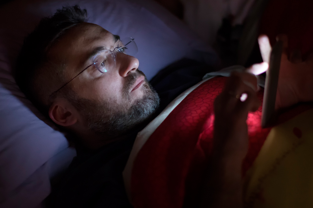 Homem usando smartphone durante a madrugada.