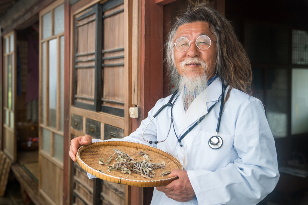 Um médico naturopata segurando uma bandeja de ervas secas.