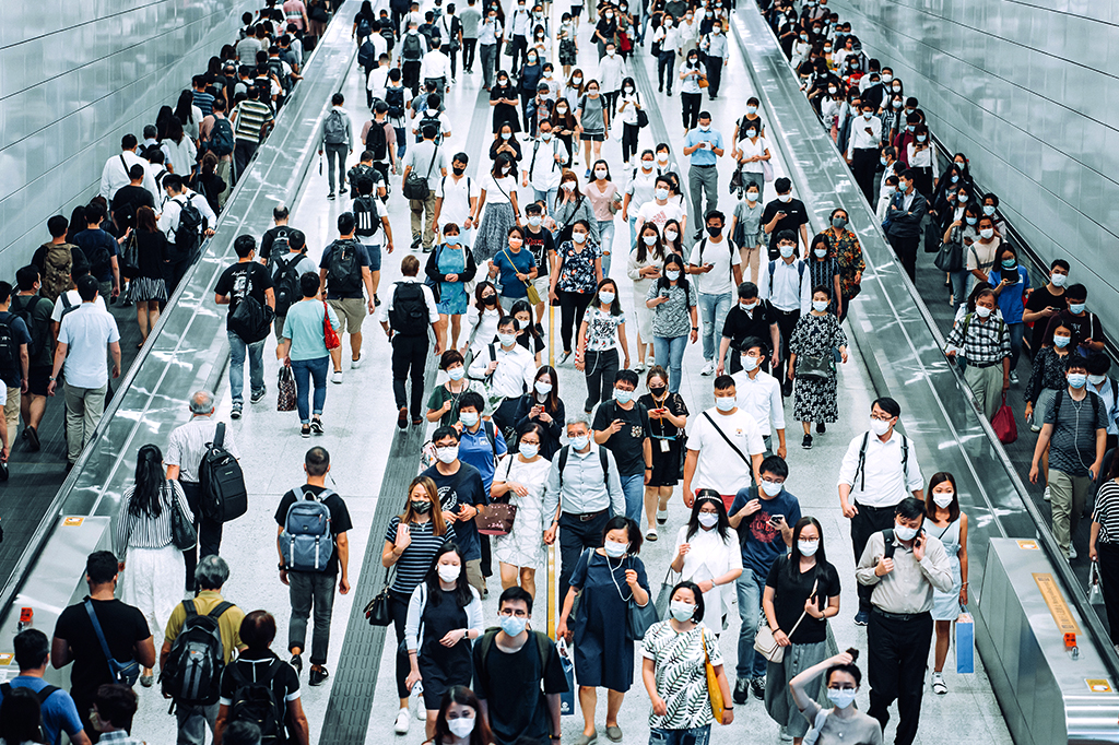 Multidão de passageiros com máscara protetora andando pelas plataformas da estação de metrô em Hong Kong.