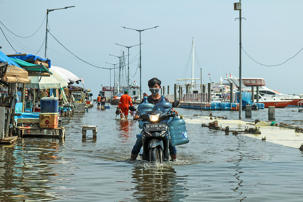 Residentes caminhando através das enchentes que atingiram Jacarta, capital da Indonésia.
