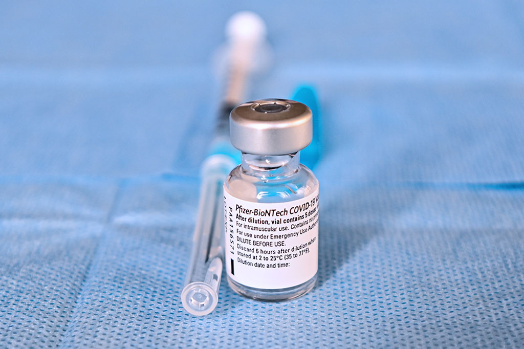 Um frasco da vacina Pfizer-BioNTech no centro da imagem.