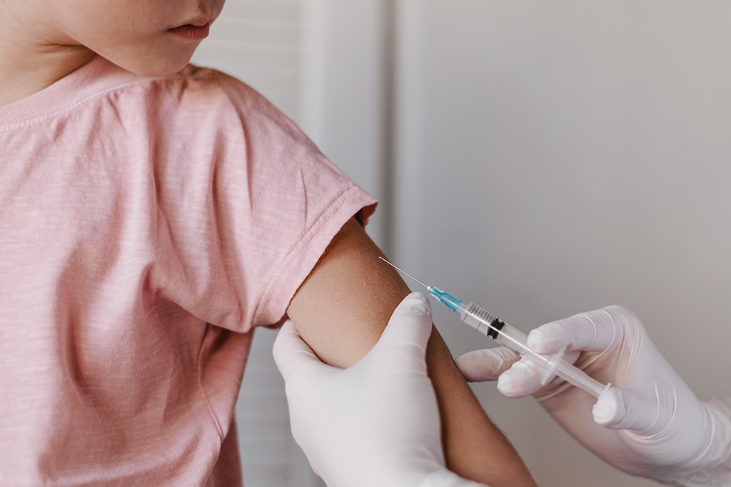 Criança tomando vacina no braço esquerdo.