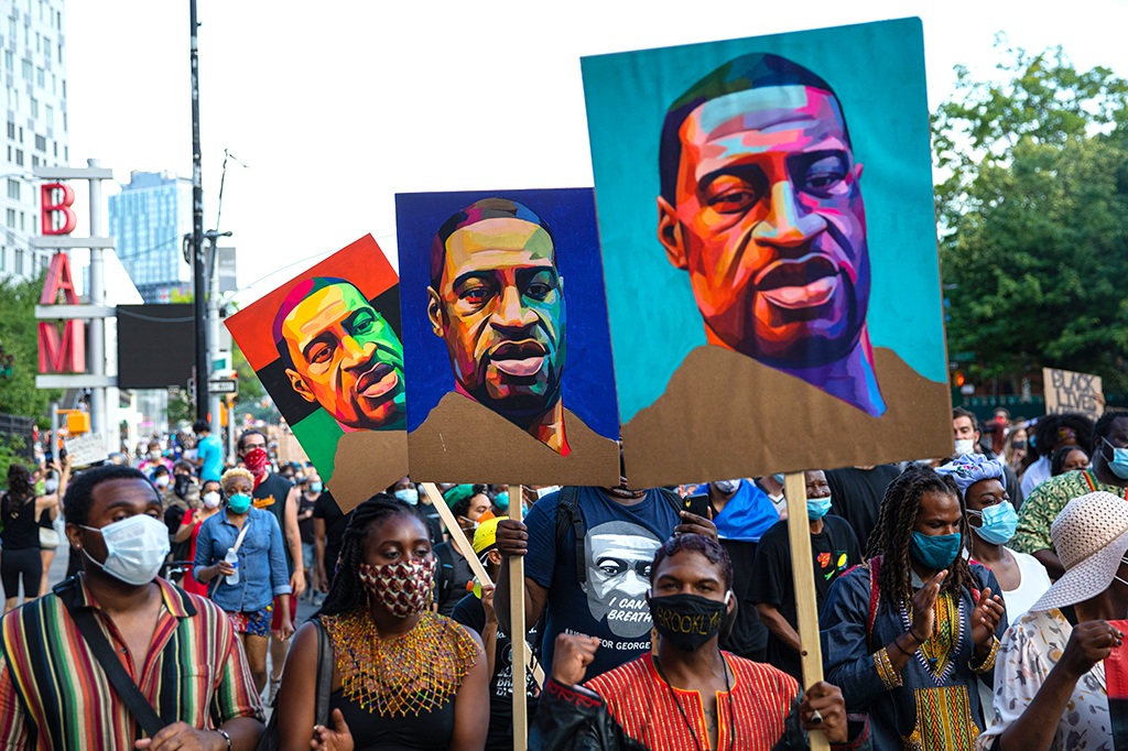Pedestres carregam cartazes com a foto de George Floyd, durante a marcha de protesto em 19 de junho de 2020 no bairro do Brooklyn, em Nova York.