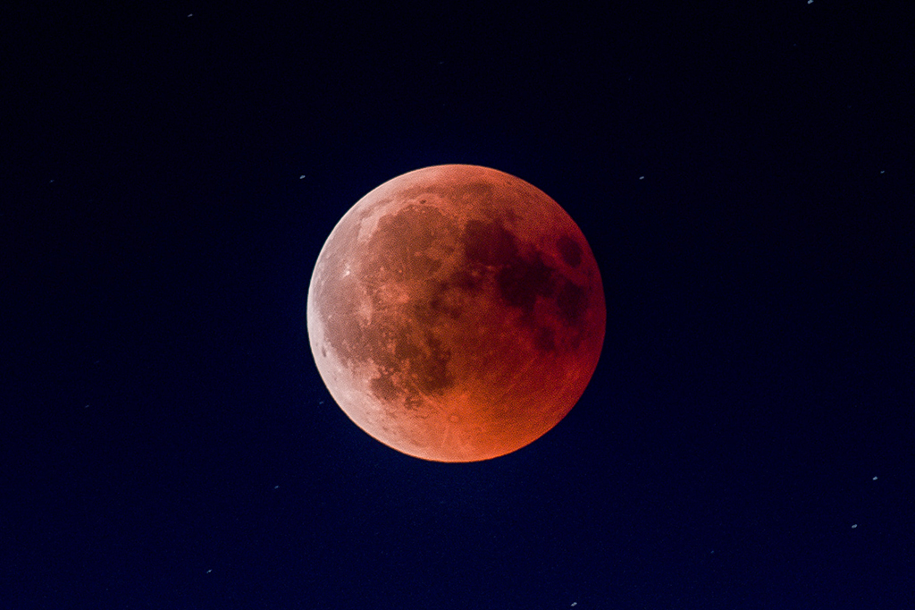 Foto da lua eclipsada, com tom avermelhado.