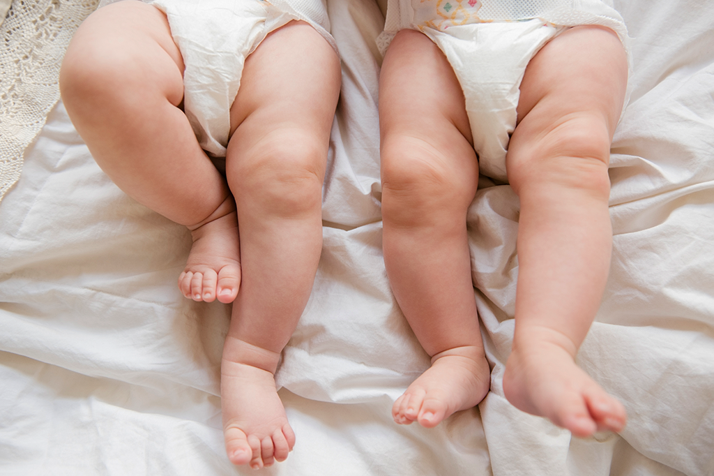Foto mostrando as perninhas de dois bebês.