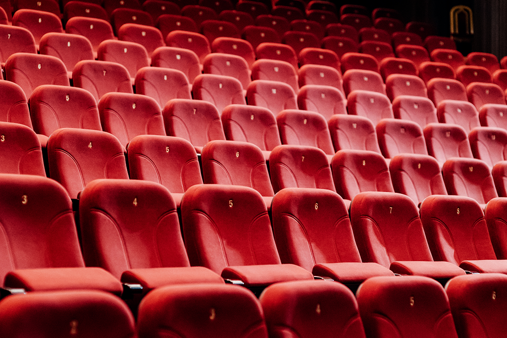 Foto mostrando várias cadeiras de cinema vazias.