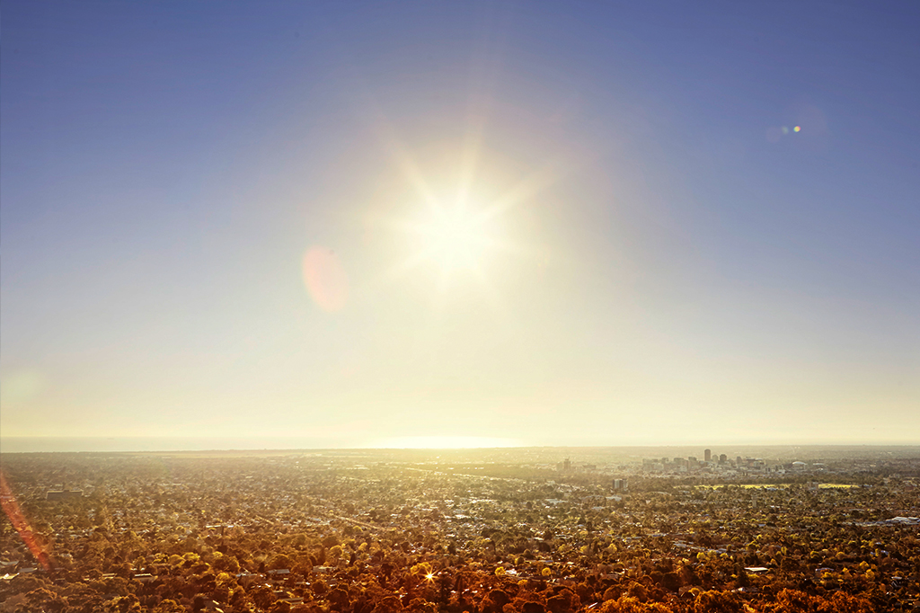 Foto de cidade vista de cima com sol incidindo sobre ela.
