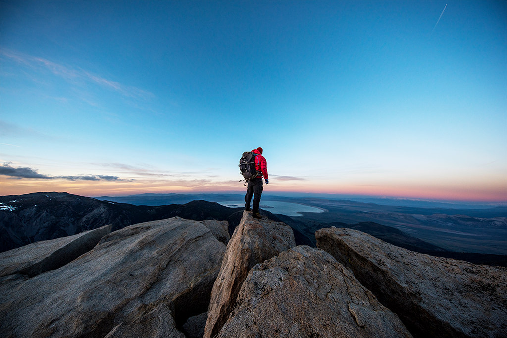 Pessoa no topo de uma montanha olhando para o horizonte.