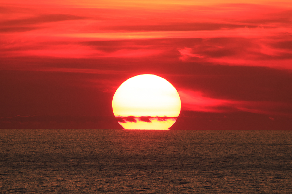Foto do sol se pondo no mar.