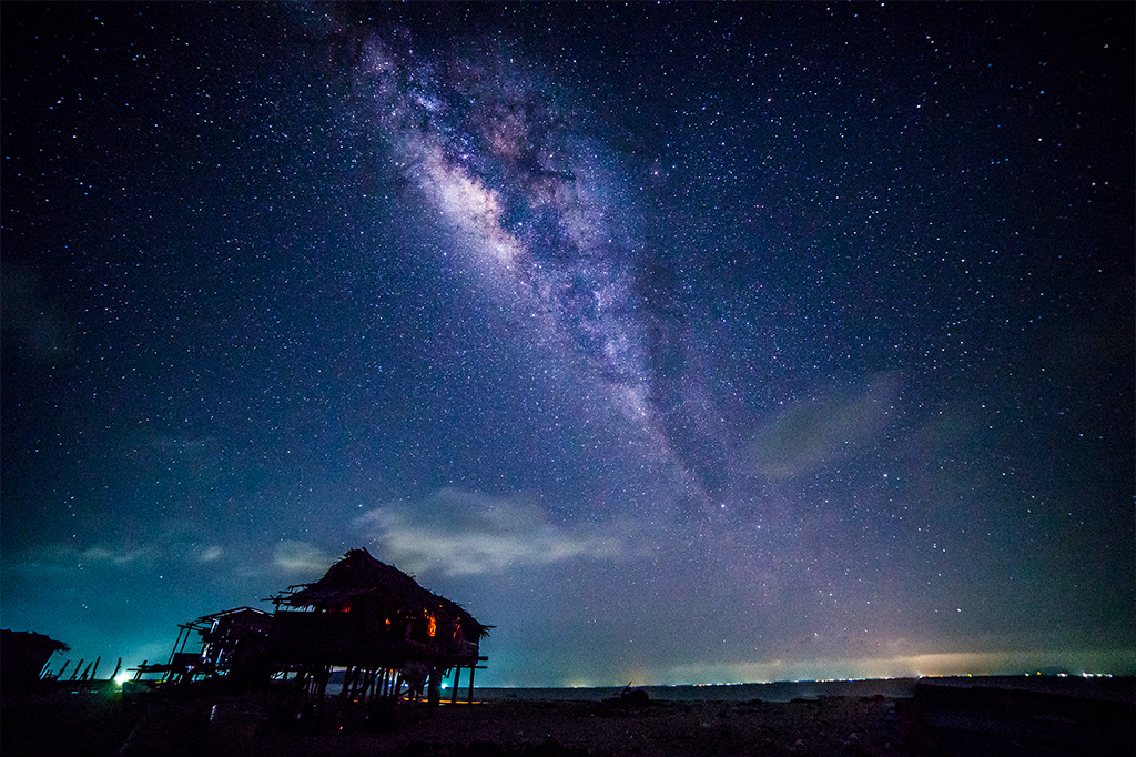 Foto de cabana com a Via Láctea de fundo no céu.