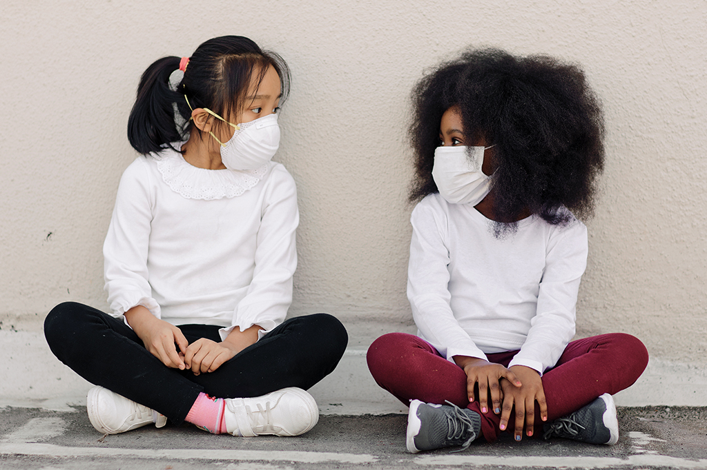 Duas meninas se olhando usando máscara.