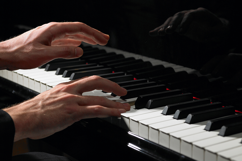 Close nas mãos de pessoa tocando piano.