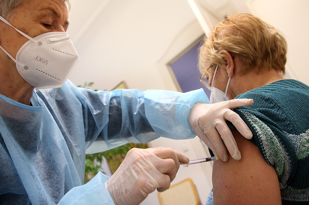 Mulher recebendo terceira da vacina contra covid.