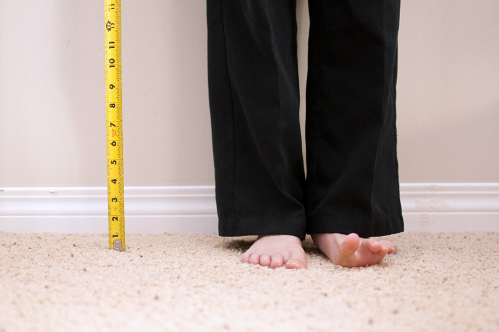 Pernas de uma pessoa ao lado de uma fita métrica.
