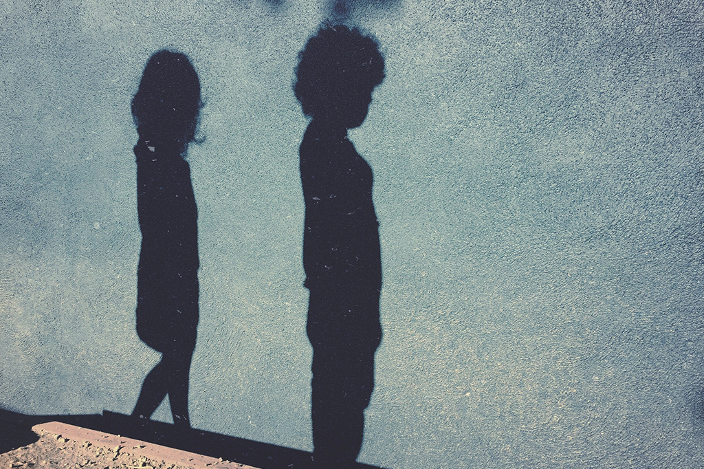 Sombra de duas crianças projetadas numa parede.