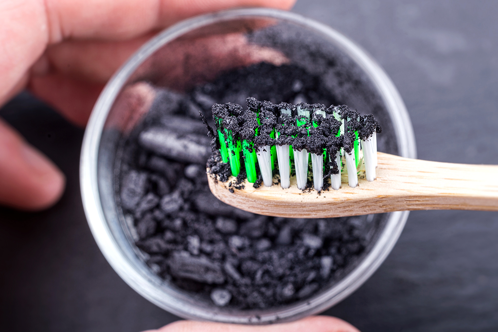 Foto de uma escova de dentes suja de carvão ativado.