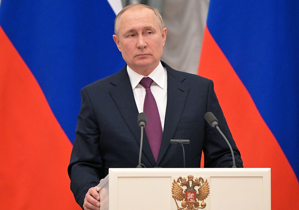 Vladimir Putin em frente à bandeira da Rússia