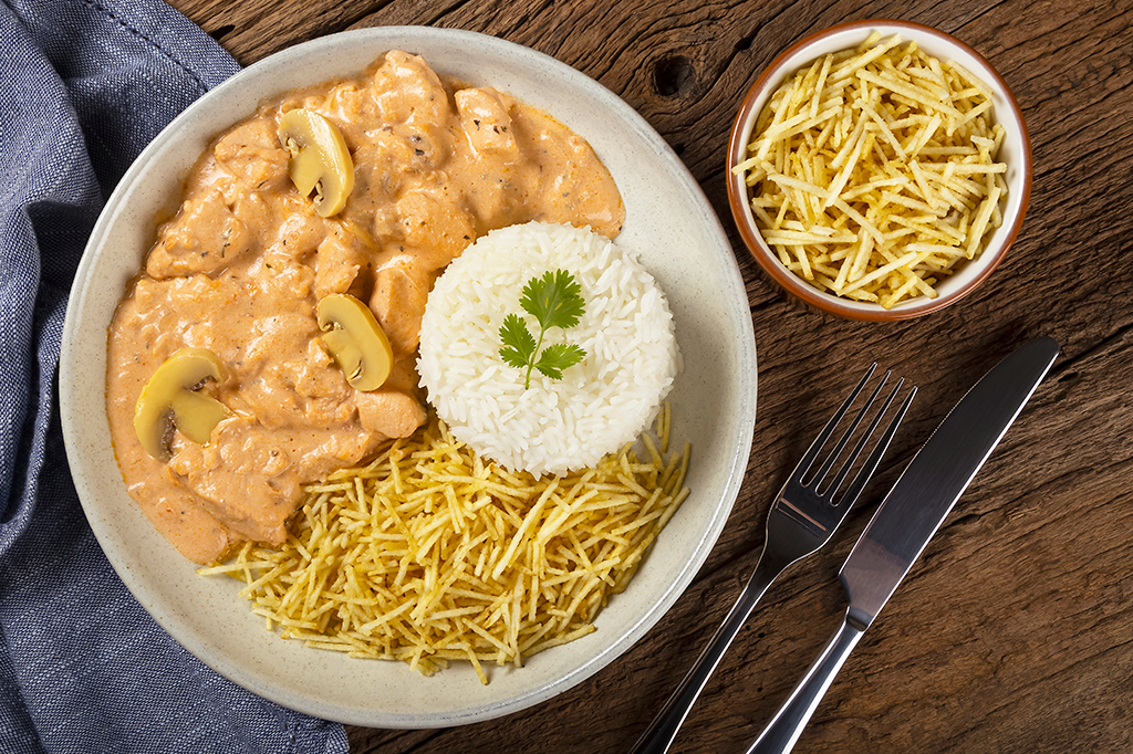 Foto de um prato de estrogonofe com arroz e batata palha.