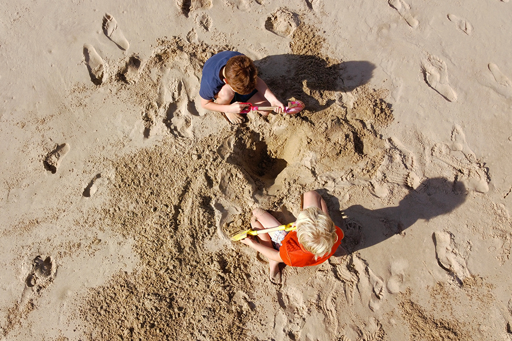 Foto de duas crianças cavando areia.