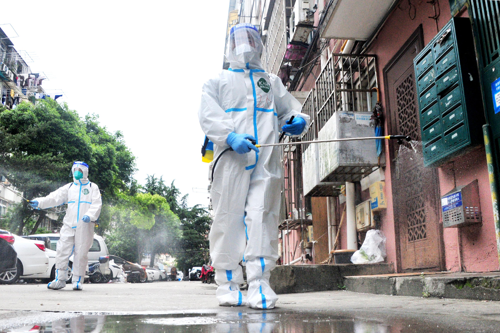 Voluntários com roupa de proteção desinfectando áreas da cidade.
