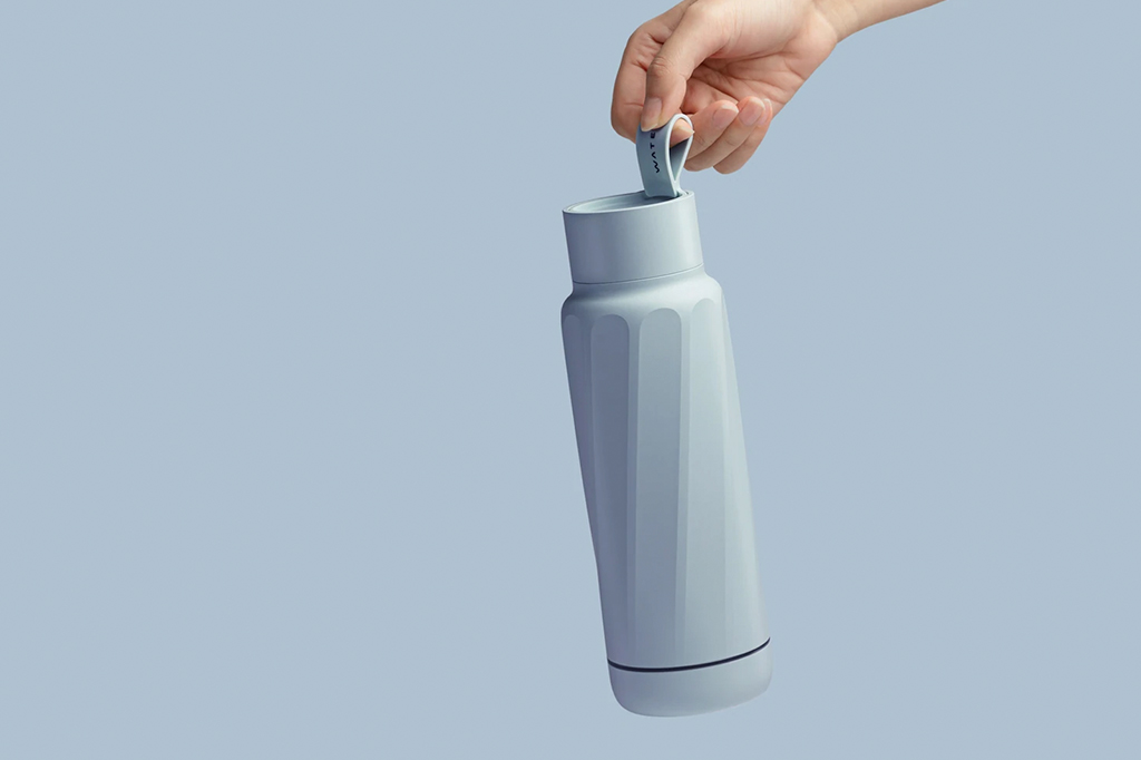 Imagem close up de uma mão segurando uma garrafa de água.