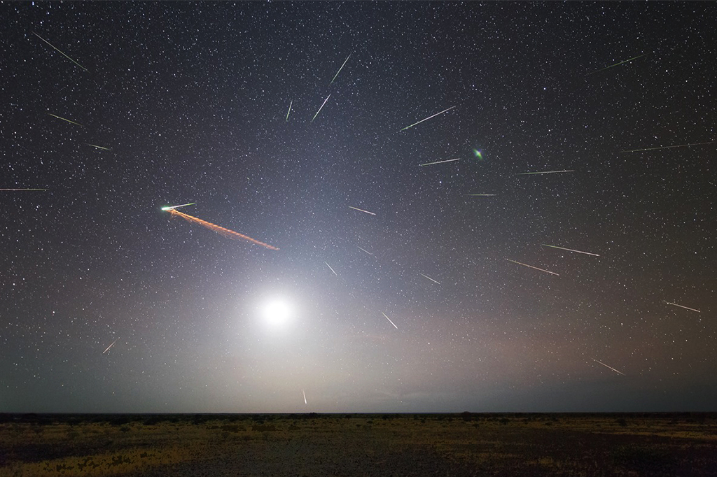 Imagem de um plano aberto, no céu vê-se chuvas de meteoros.