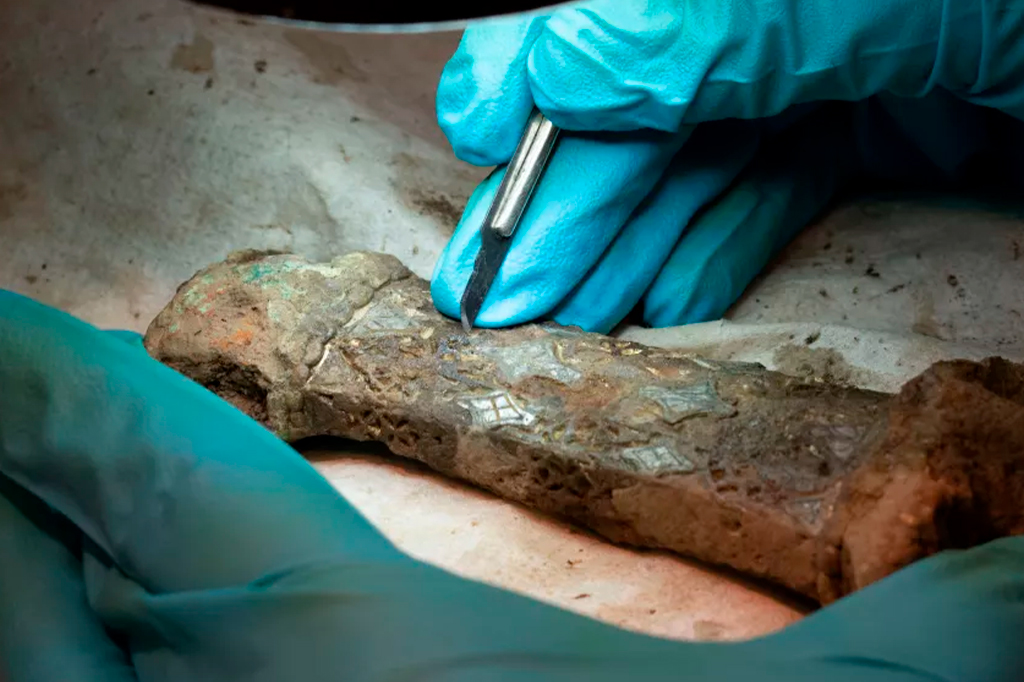 Um pesquisador examina os restos de uma espada da Era Viking descoberta na Noruega.