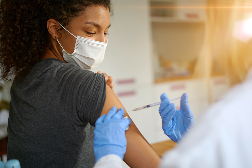 Profissional de saúde aplicando vacina no braço de paciente.
