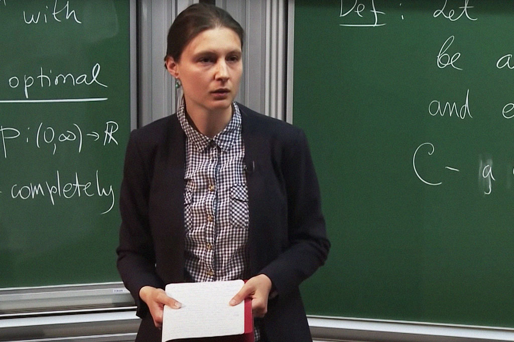 Foto da matemática ucraniana Maryna Viazovska em frente a uma lousa.