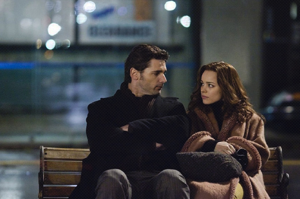 Cena do filme Te Amarei Para Sempre, em que os personagens principais estão sentados em um banco, na rua, olhando um para o outro.
